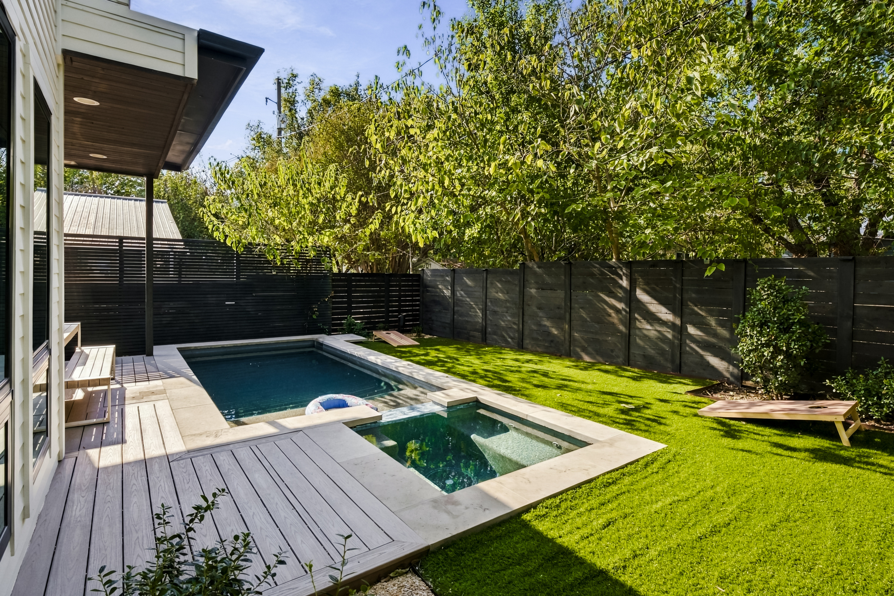Elevated deck view showcases the pool and lush turf backyard.