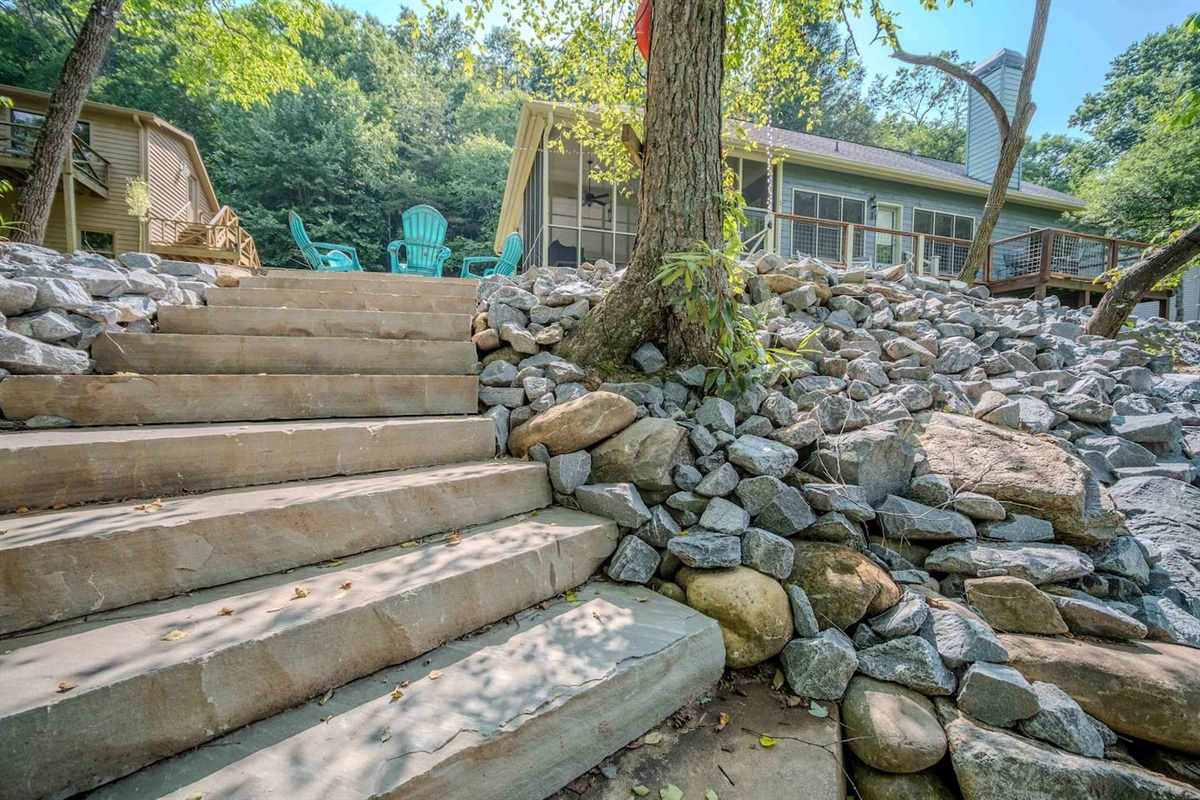 A beautiful stone staircase leads you from the river’s edge to the cozy fire pit and deck area above — a perfect path from nature to comfort, inviting you to relax and soak in the serene riverfront atmosphere.