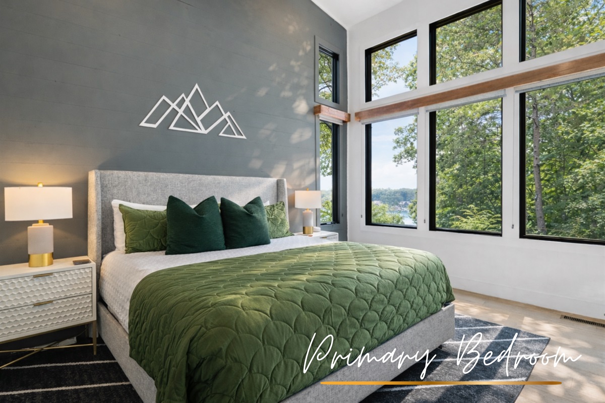 A vibrant and airy primary bedroom with large windows, plush bedding, and a serene forest view.
