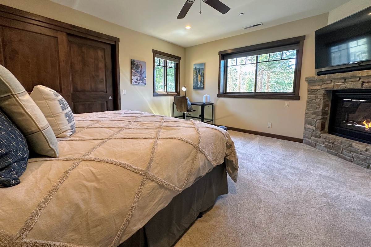 Retreat to the calming blue hues of the primary bedroom, complete with a plush king bed, cozy fireplace, dedicated workspace, and a large smart TV. Soaring windows flood the space with light and frame sweeping views of Canyon Lodge—your personal haven of c
