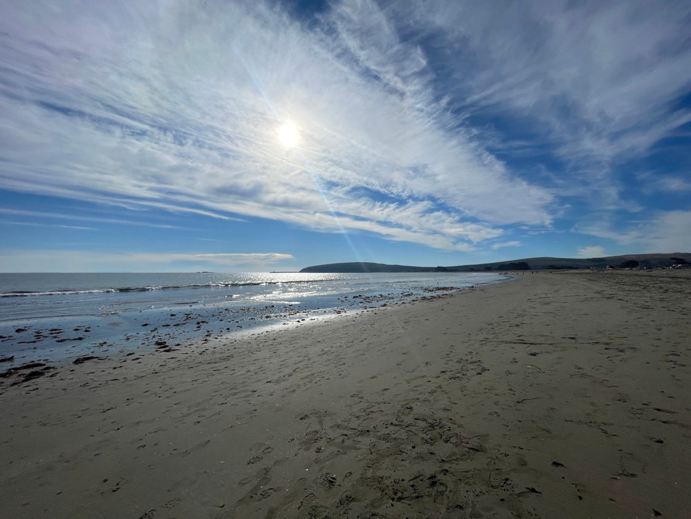 Sunlight and wispy clouds above the sandy beach