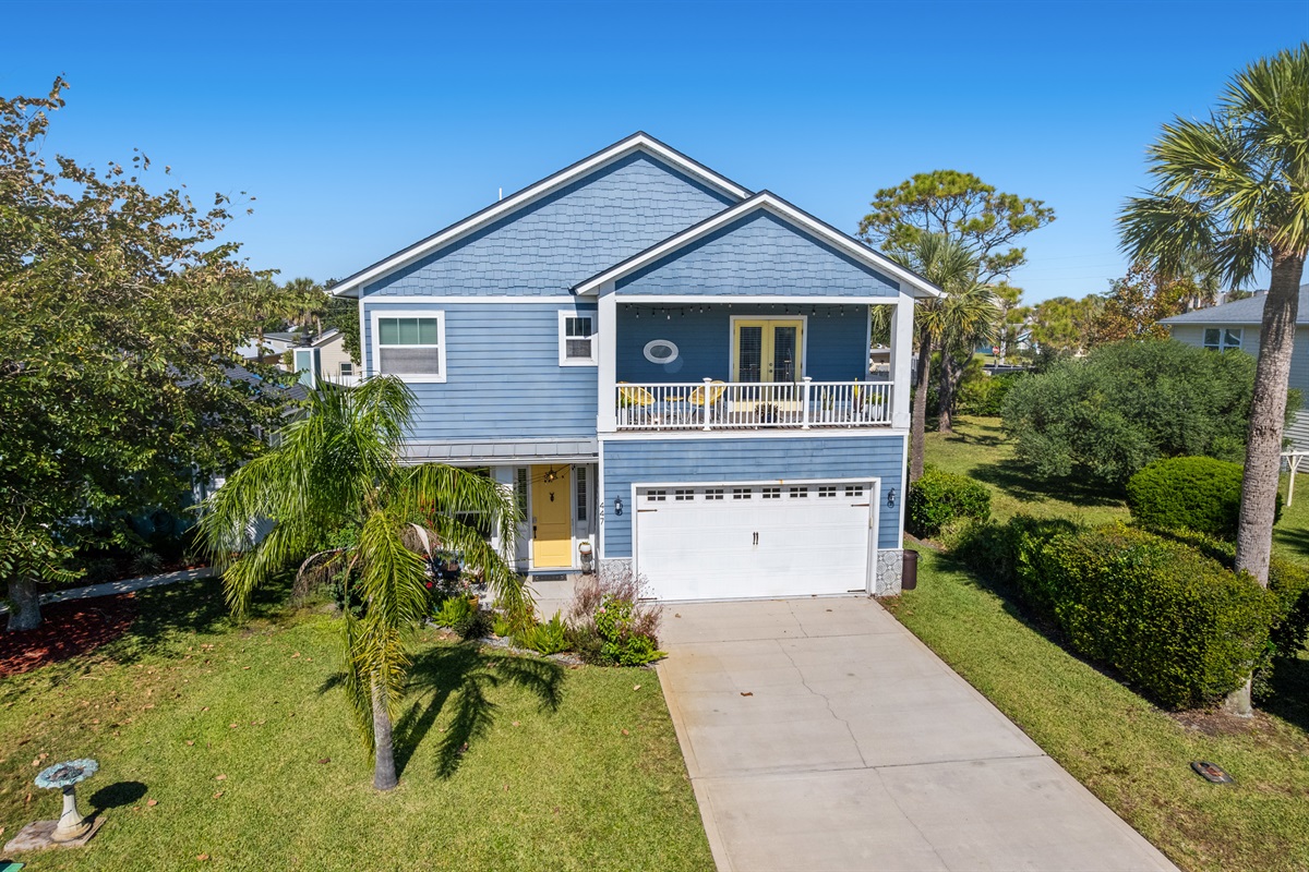 Charming coastal home with inviting balcony and tropical landscaping.
