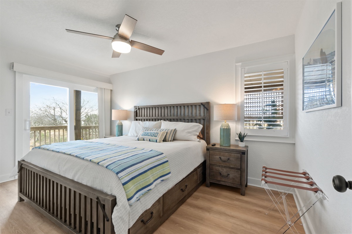 Queen Bedroom #1 – Bright bedroom with a queen bed and deck access, filled with natural light.