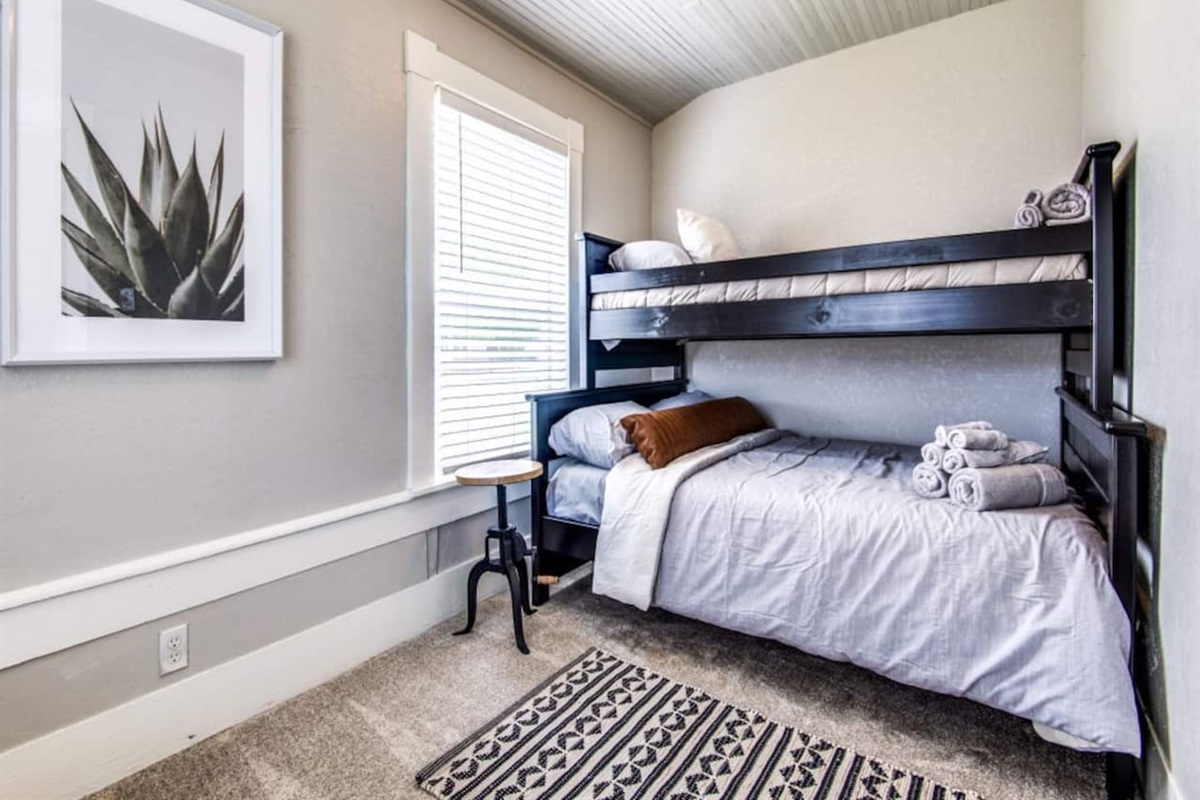 Twin-over-full bunk bedroom with shiplap ceiling, natural light, and hardwood floors. Sleeps 3 in this modern farmhouse Airbnb in Aubrey TX. Pack and Play available on request. Total capacity 7 guests near downtown Aubrey dining.