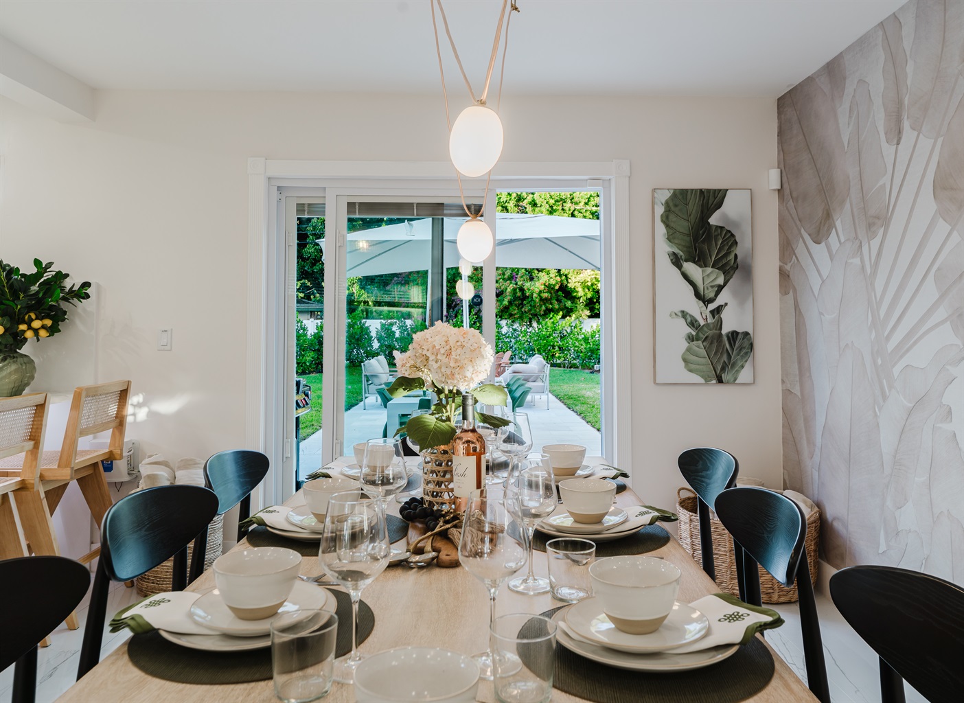 Designer dining room featuring a Gwyneth Paltrow GOOP statement light, custom wallpaper, and seating for 12. Backlit counter seating and seamless access to the patio and backyard make this space ideal for family meals and entertaining.