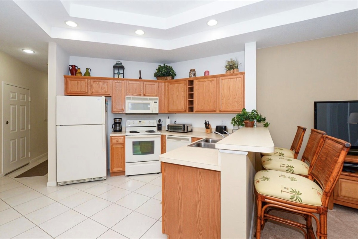 Bright kitchen and dining area featuring full-size appliances, breakfast bar seating, and an open flow into the living space.
