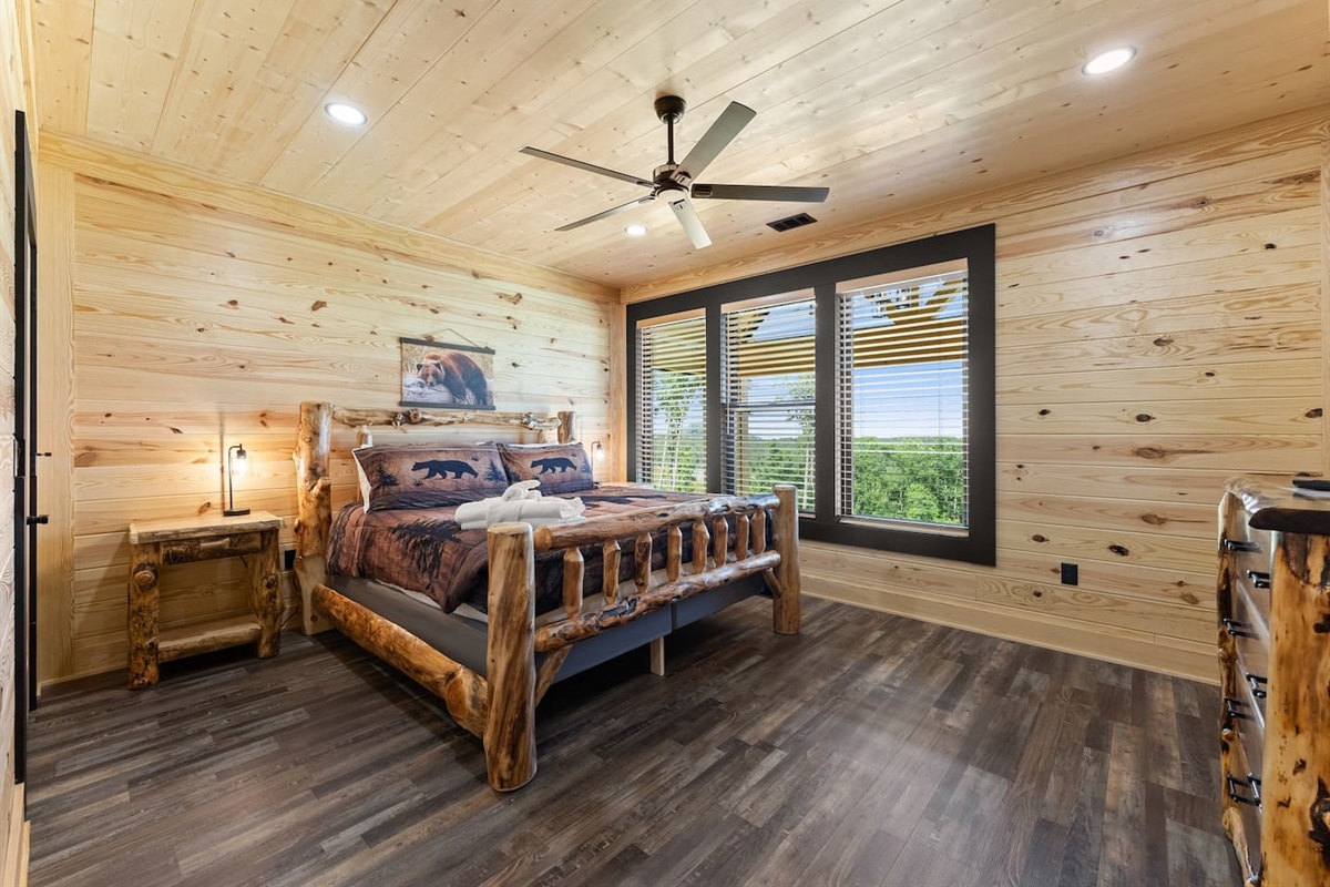 This sun-filled bedroom features handcrafted log furniture, cozy bear-themed bedding, and sweeping views of the North Georgia treetops.