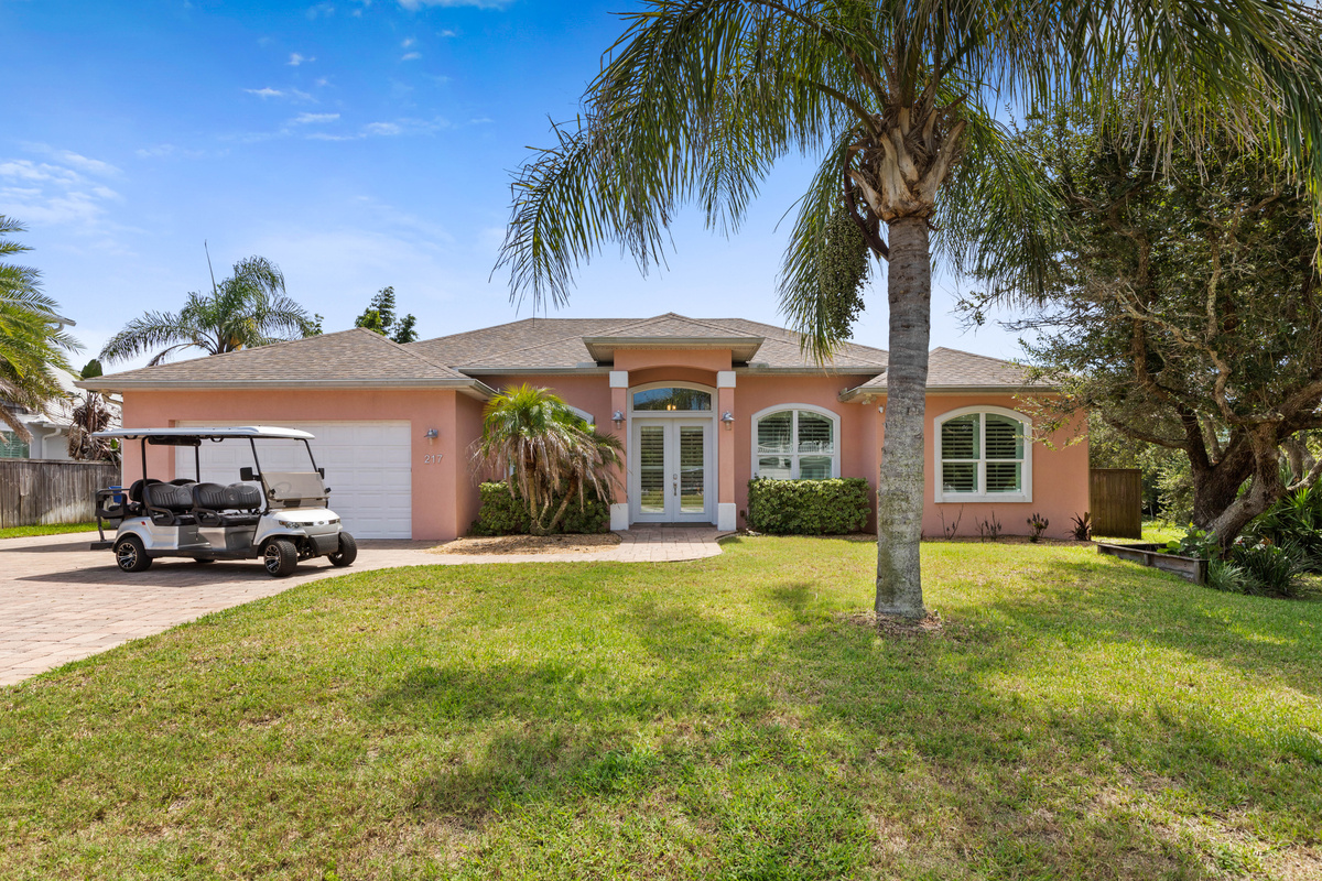 Easy arrival with a paver driveway and wide lawn; the cart shown is an optional golf cart rental, booked separately.