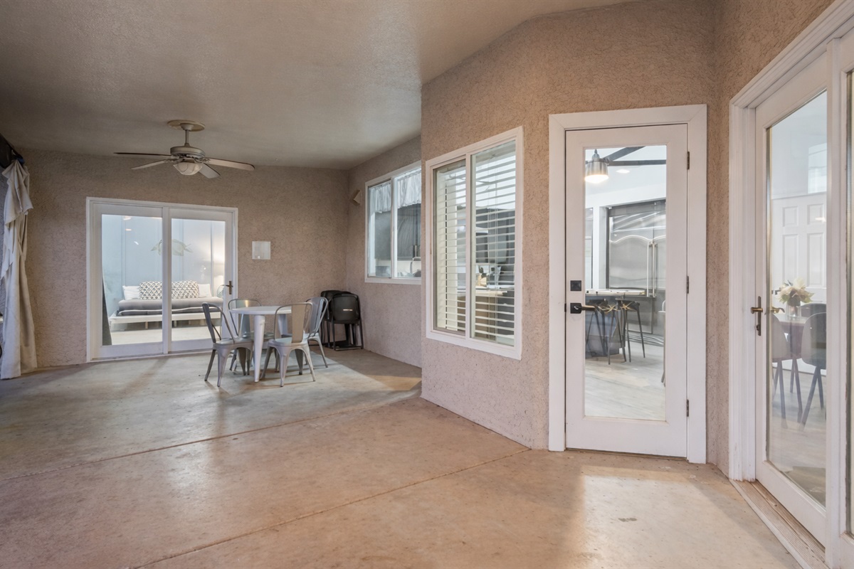 Dine outdoors under the covered patio with ceiling fans and fresh air just steps from the kitchen and pool.