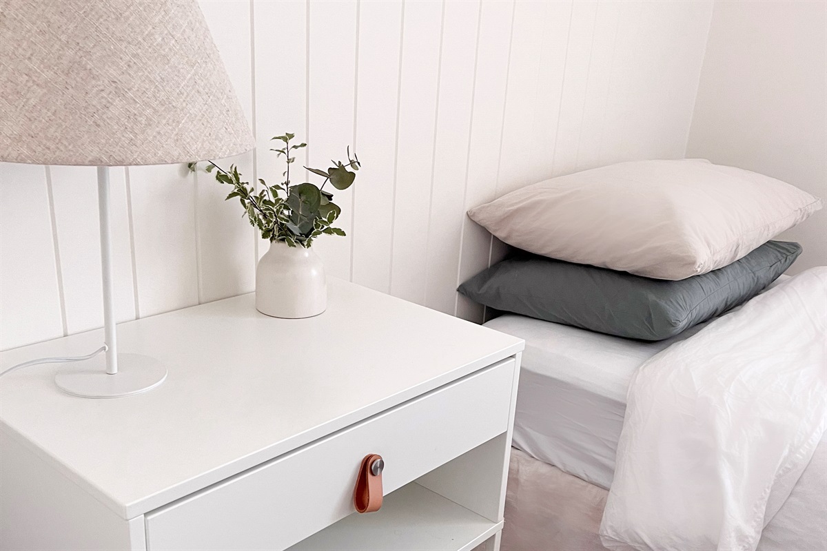 The bedside lamp adds useful reading light beside the bed, with a simple side table and soft bedroom styling.