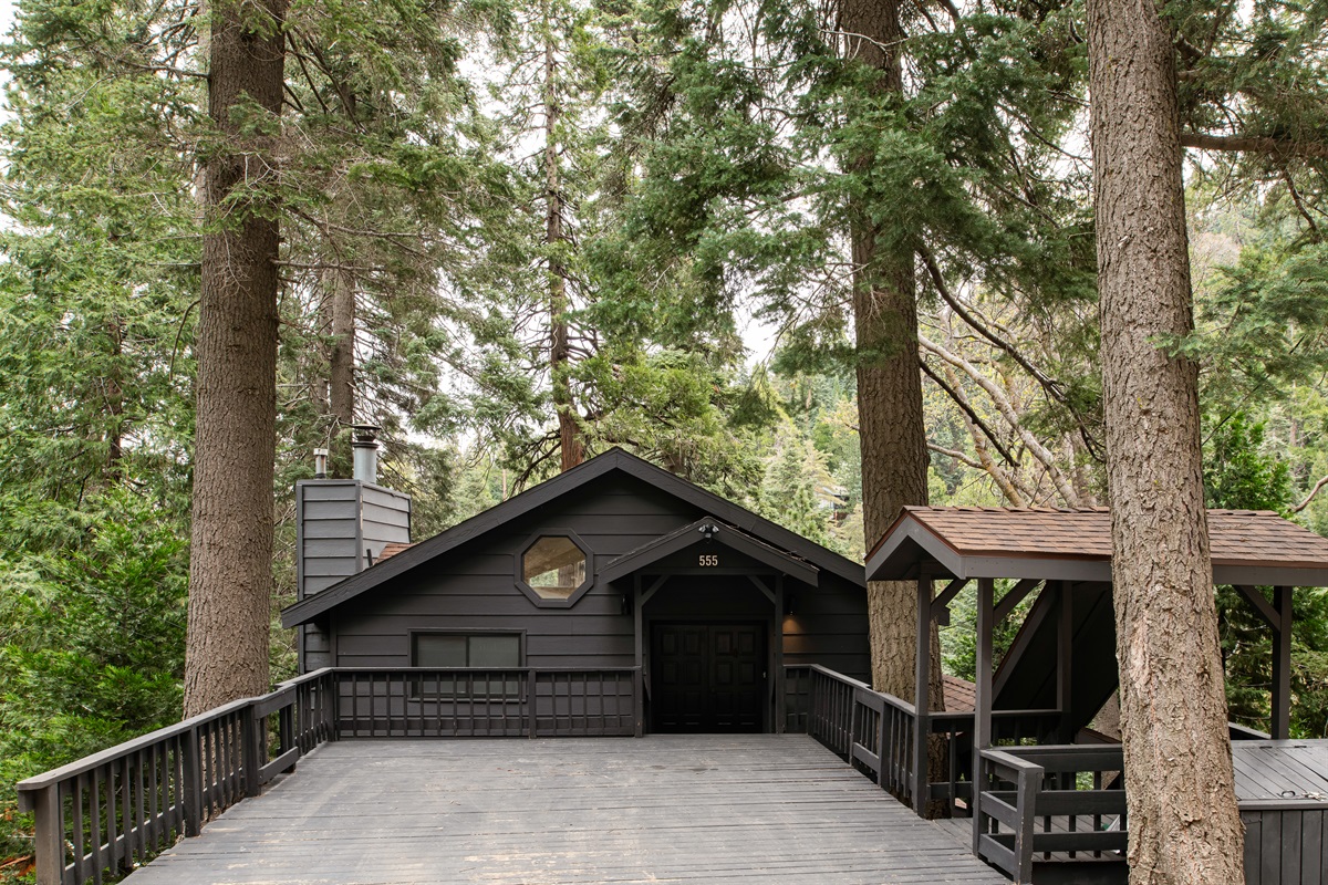 Welcoming cabin exterior with 2-Car Driveway Deck, surrounded by tall pines—your private mountain escape starts right at the front door.