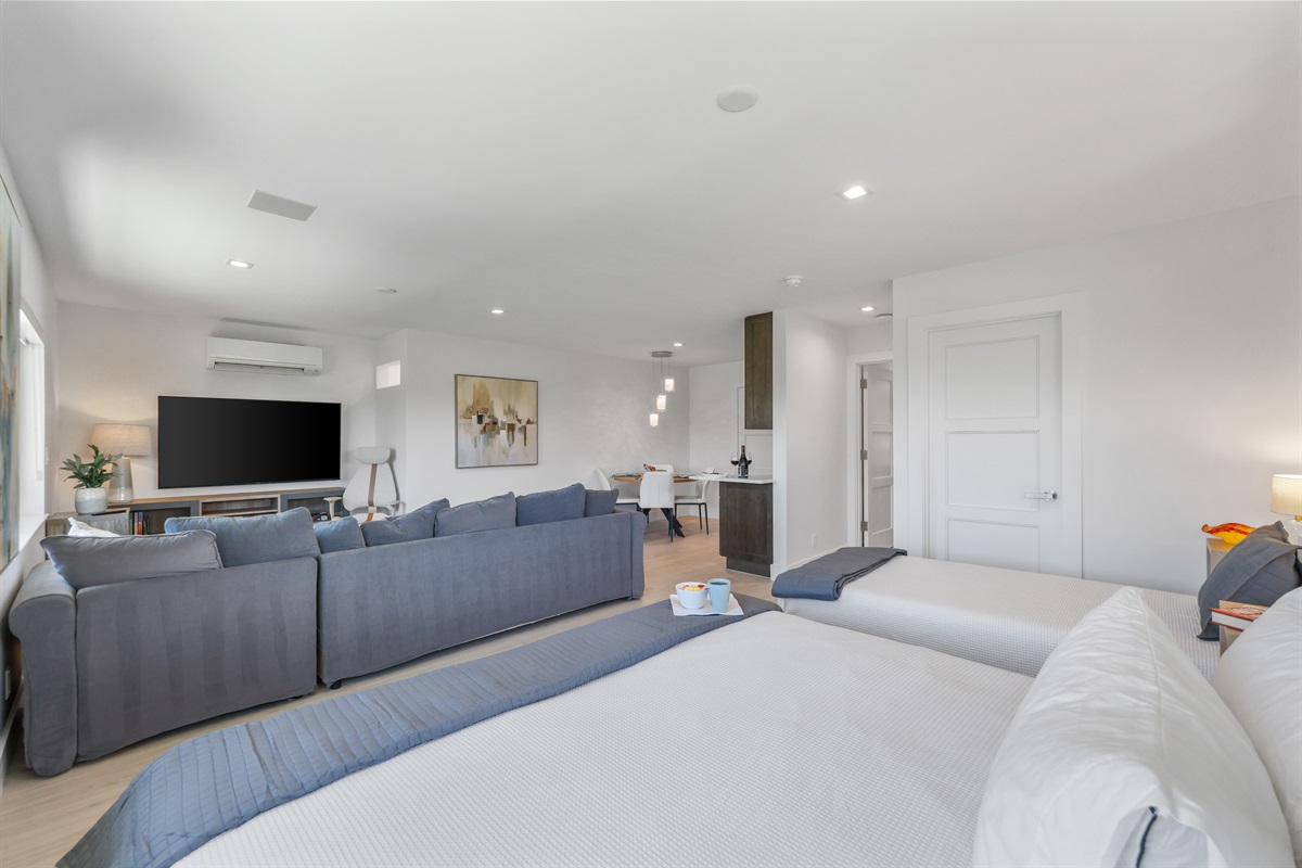 Spacious open-plan layout – king bed, twin bed, sectional lounge, and 65” Smart TV