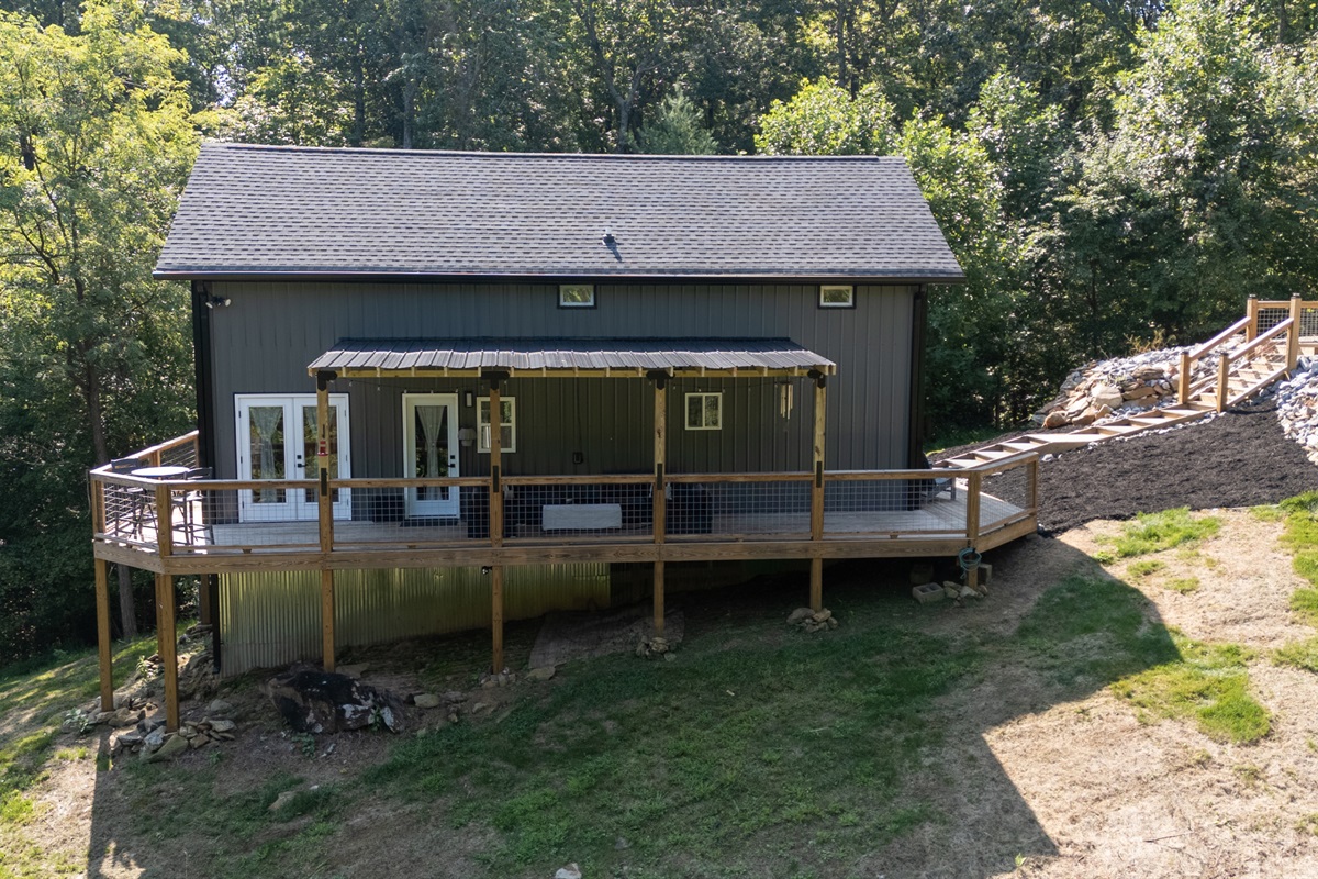 Exterior view of Heart Ridge with wraparound deck and wooded backdrop.