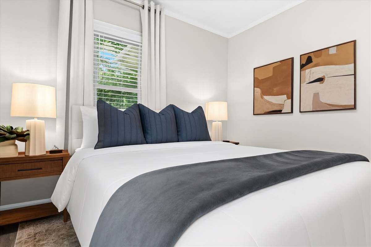 Bright queen bedroom with plush bedding and modern art