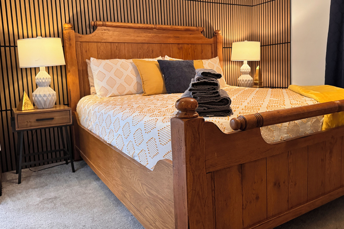 King-sized bed with an en-suite bathroom and walk-in closet. It includes blackout curtains, a full-length mirror, 50” TV, side chair, and table, as well as USB and USB-C charging ports & Pak-N-Play portable crib.