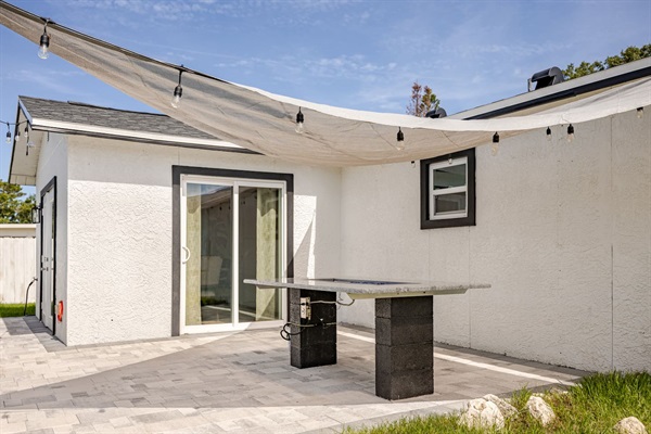 Propane glass fire pit table under a shaded area with overhead lights