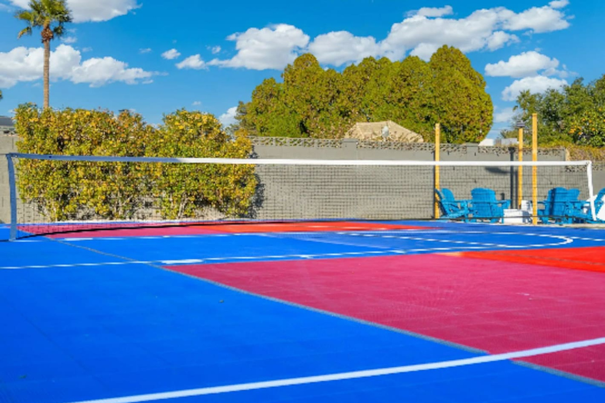 A full volleyball court adds even more room to play, framed by lush greenery and blue Adirondack chairs for anyone cheering from the sidelines.