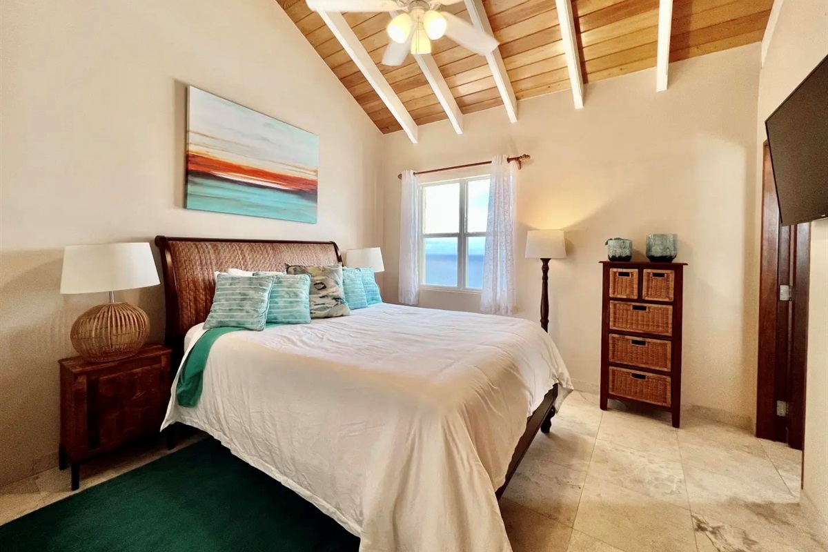 Guest bedroom with vaulted ceilings and ocean view—wake up to blue water every day.