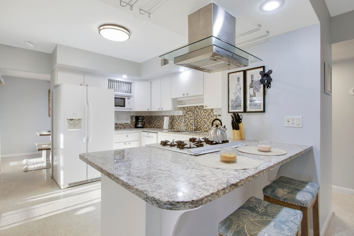Kitchen with granite counters, stove and bar area.