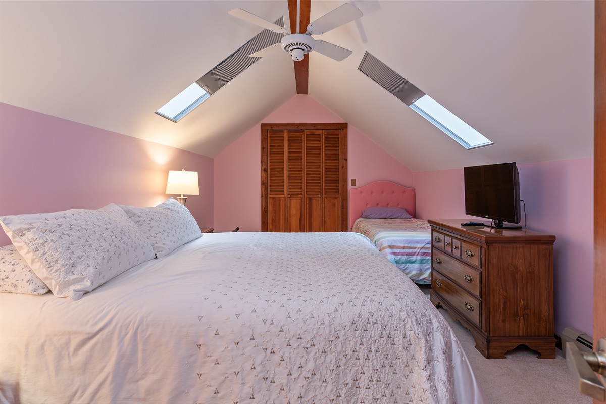 Bright loft bedroom with vaulted ceilings and skylights — drift to sleep under the stars.