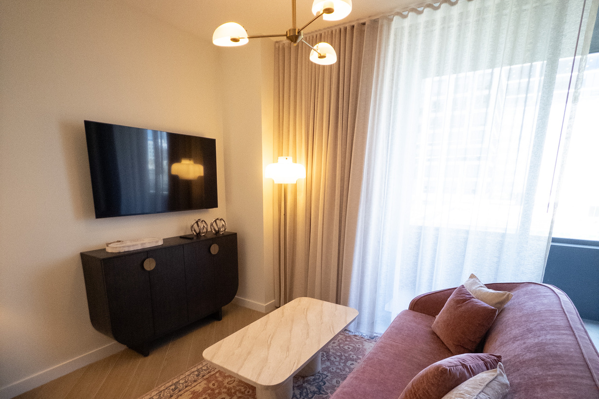 Cozy media corner - wall-mounted smart TV, soft seating and warm sconce light.