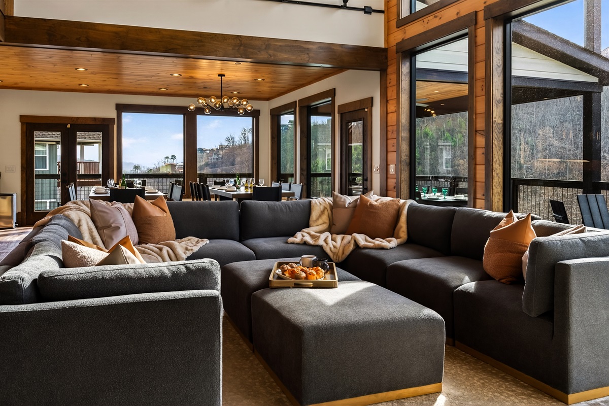 Gather beneath 30-foot vaulted ceilings surrounded by a wall of windows. Relax on the large sectional sofa beside the luxury fireplace with stunning floor-to-ceiling stone, creating a warm and unforgettable mountain lodge atmosphere.