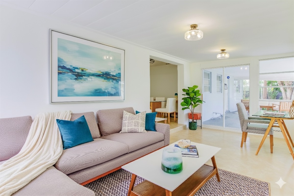 Bright Florida Room with wraparound windows, cozy seating, a TV, and a stylish glass desk overlooking the heated saltwater pool — perfect for relaxing or remote work.