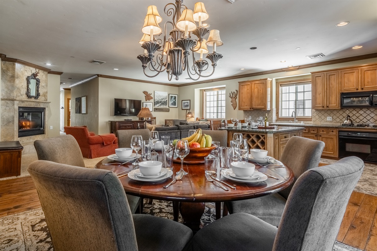 The Charming Chalet's round dining table is set beside floor-to-ceiling windows, filling the space with natural light.