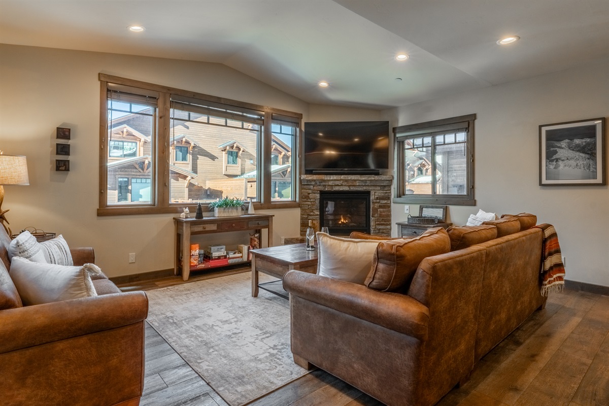 At Triple Black, mountain light pours through expansive windows, framing a warm fireside living space with oversized seating and room for everyone to gather.