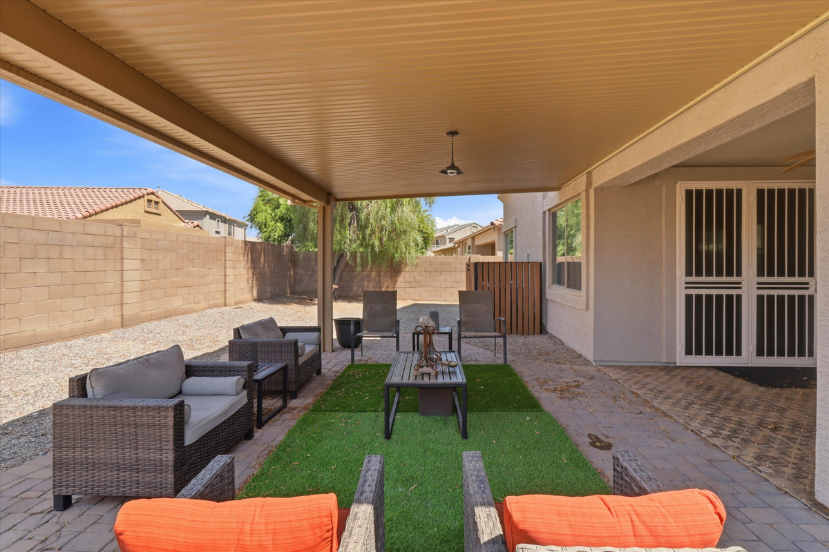 Covered backyard patio with lounge seating, BBQ grill, and space to hang out outside.