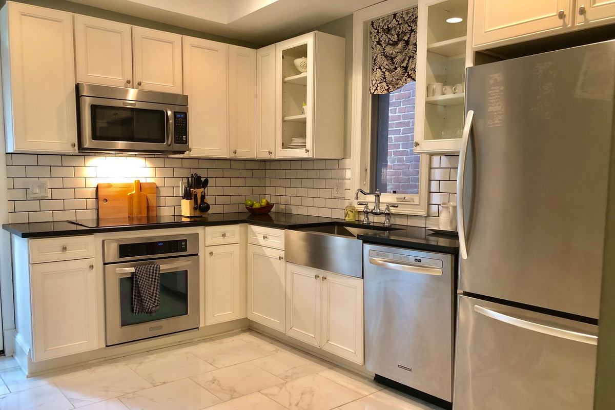 Whip up meals with ease in this chef-friendly kitchen featuring stainless steel KitchenAid appliances, sleek subway tile, and an induction cooktop.