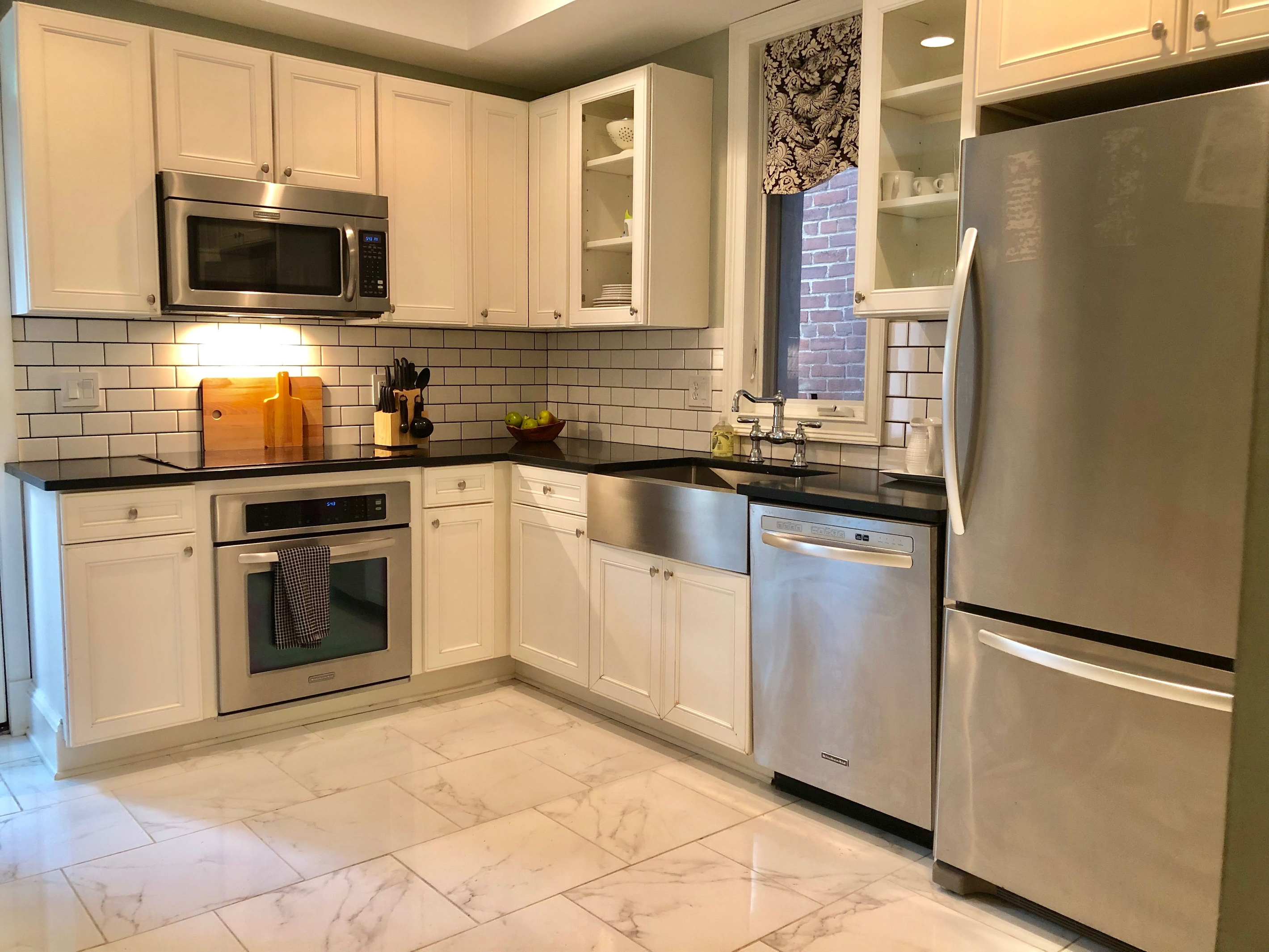 Whip up meals with ease in this chef-friendly kitchen featuring stainless steel KitchenAid appliances, sleek subway tile, and an induction cooktop.