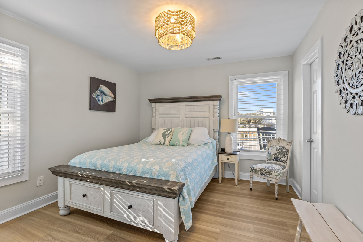 Unwind in this inviting queen bedroom featuring coastal-inspired d&eacute;cor, plush bedding, and a peaceful atmosphere for a restful night's sleep