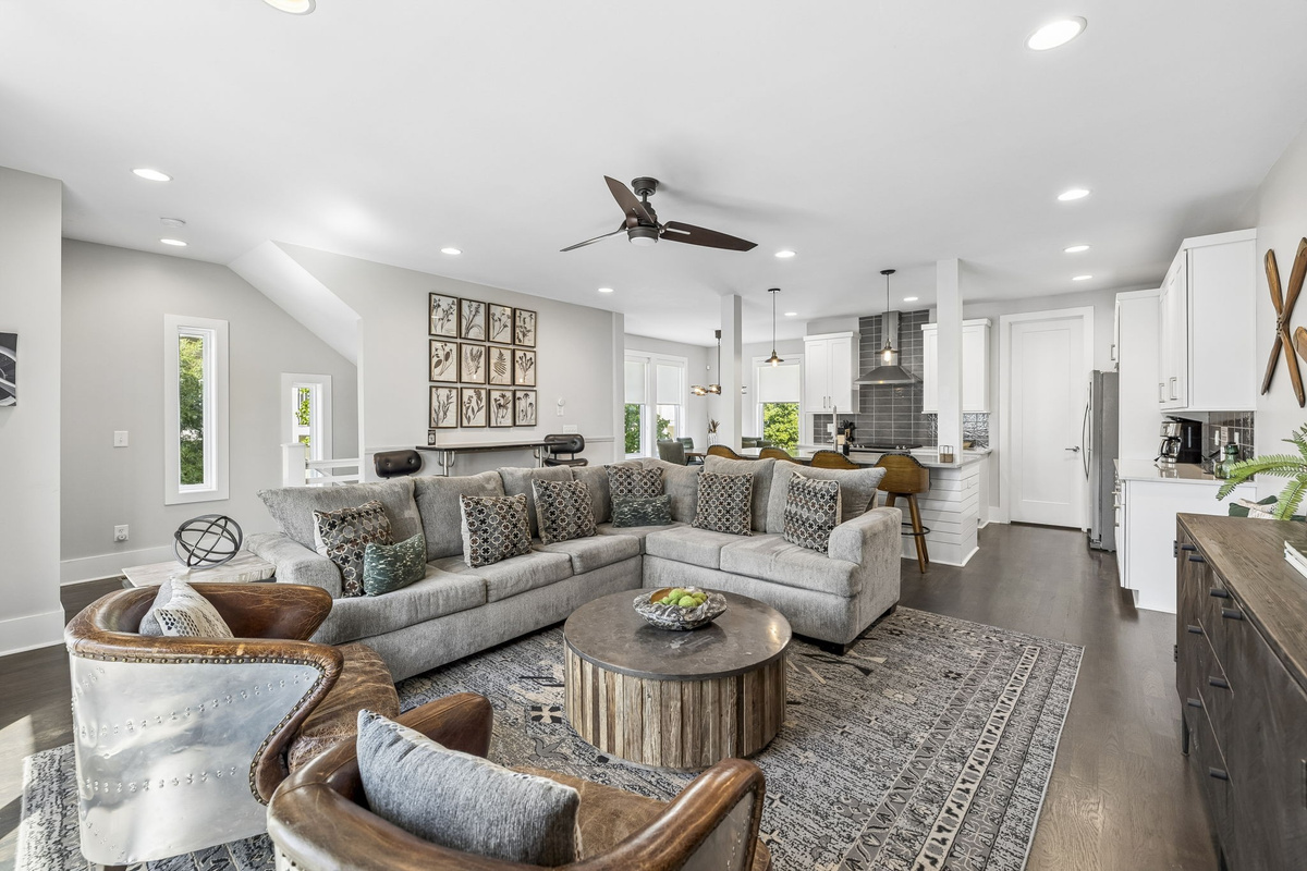 Spacious layout with plush sectional, bar seating, and sleek kitchen all in one view - Modern ceiling fans, warm wood tones, and leather accents enhance the cozy vibe - Perfect for entertaining, relaxing, or enjoying movie nights with friends and family