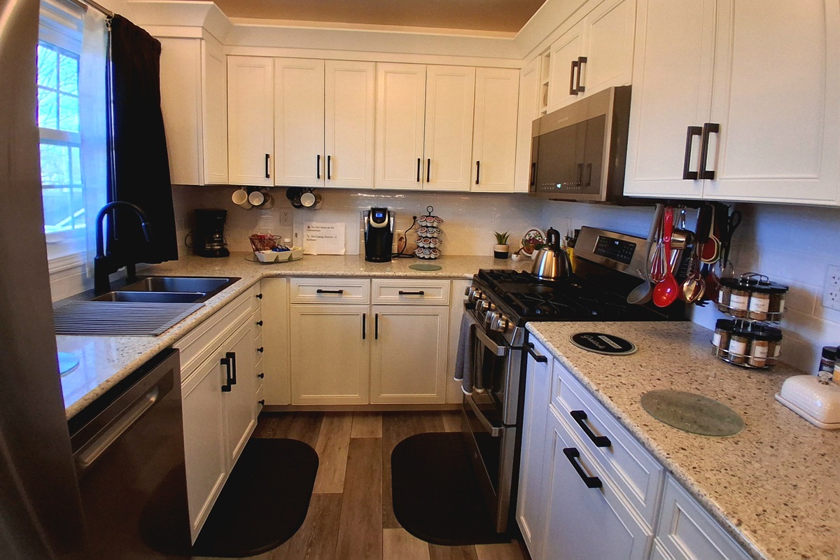 This kitchen features a sparkly peppercorn countertop & generous prep space. It includes two hidden trash cans, a bottle jet dishwasher, XL microwave & a double oven with air fryer & convection baking. The backyard window view is simply dreamy.