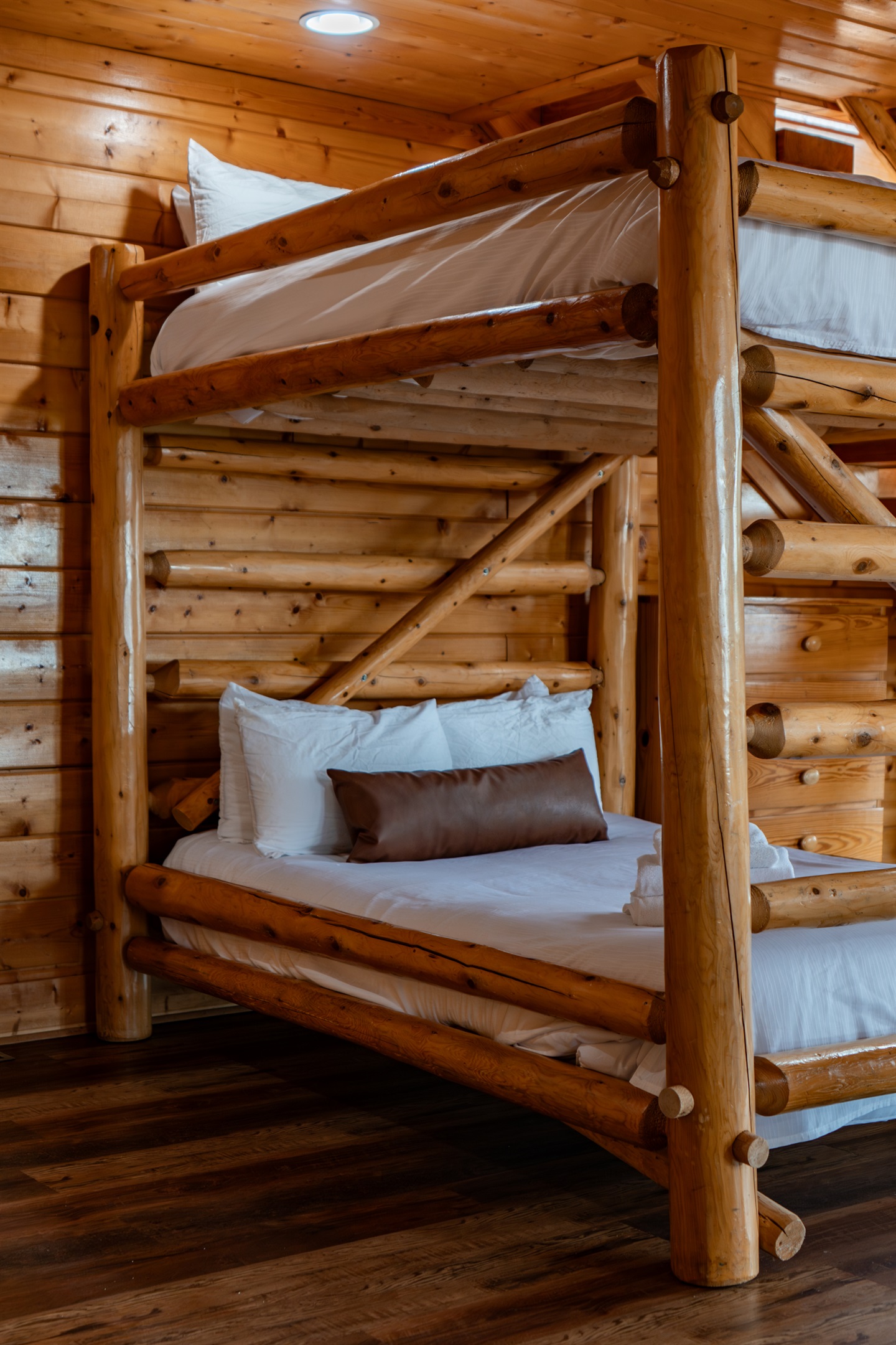 Lower level queen-over-queen log bunk — sleeps four, fresh linens, right in the heart of the game room so nobody misses a minute of the action.