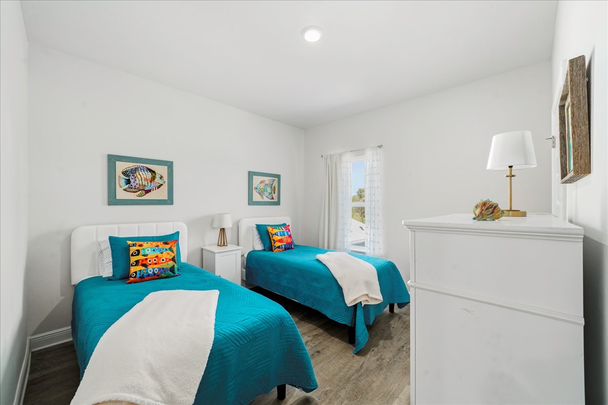Bedroom 5: twin beds, soft linens, closet, luggage stand, nightstand, and warm lamp lighting, ideal for kids or extra guests.