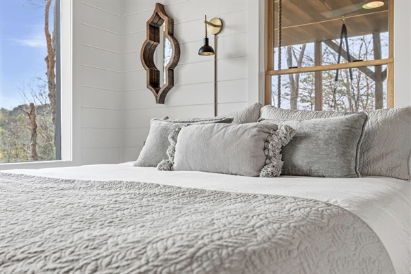 Sink into this plush king bed dressed in soft white cotton linens and a cozy textured throw. Ornate mirrors beautifully reflect the outdoors, bringing the peaceful mountain views inside while elegant wall sconces add warm ambient light.