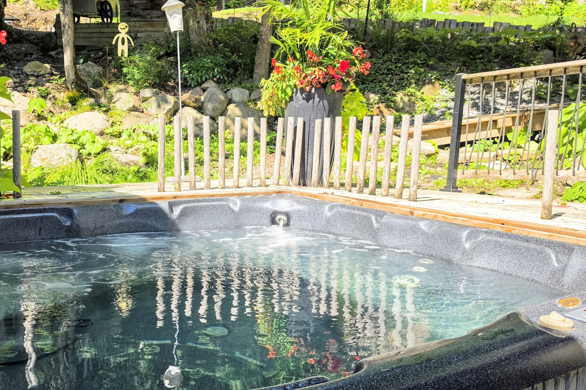Hot tub nestled between cottage veranda and the hillside