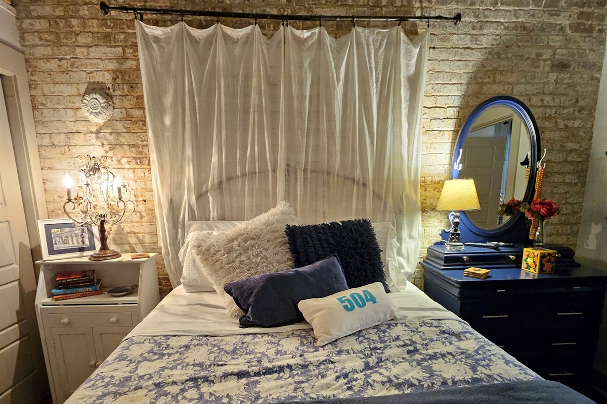 Queen bed (on risers), night stand on left, dresser w/mirror on right. NOT a window behind the drapes.