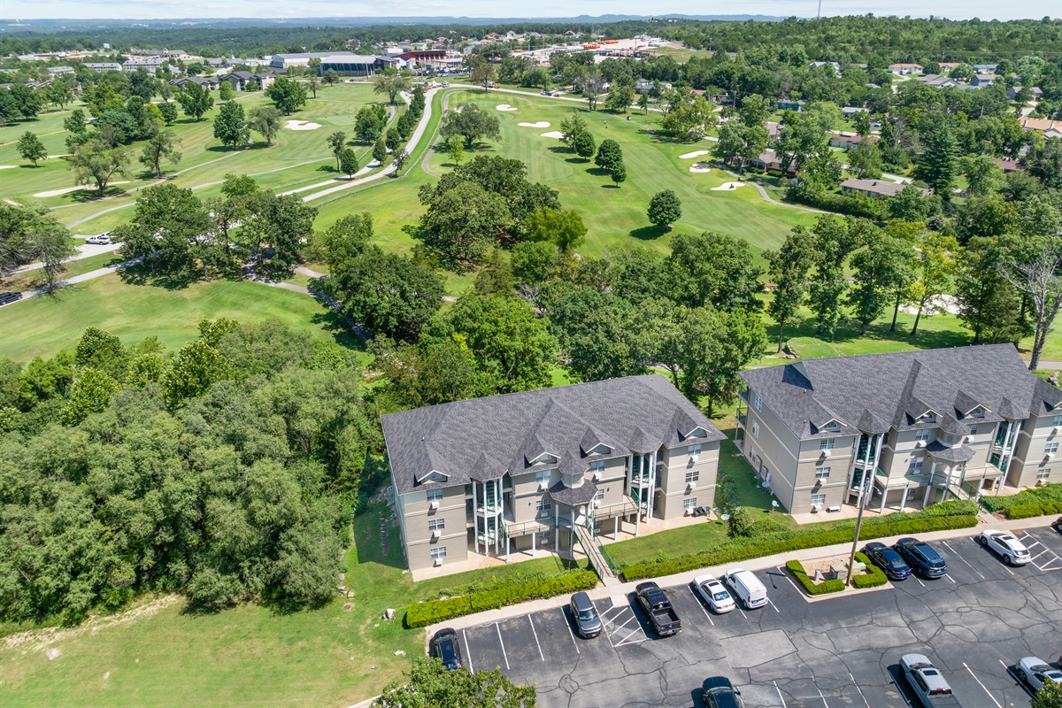 Aerial angle showing the building, parking, and golf-course setting together.