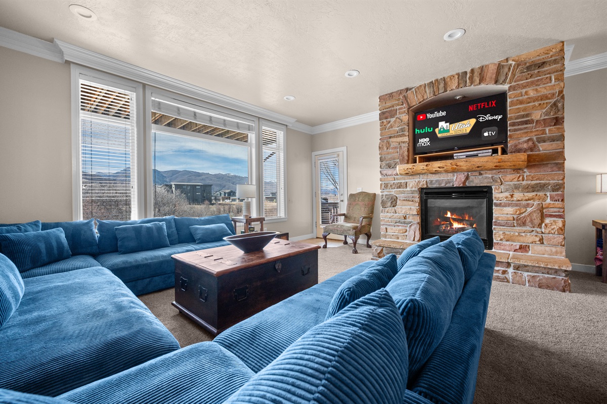 Relax in the bright, open living room with plush seating, a cozy fireplace, and stunning mountain views.