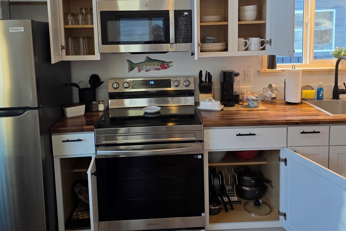 Fully stocked kitchen includes an electric range, microwave, refrigerator,  and Keurig .