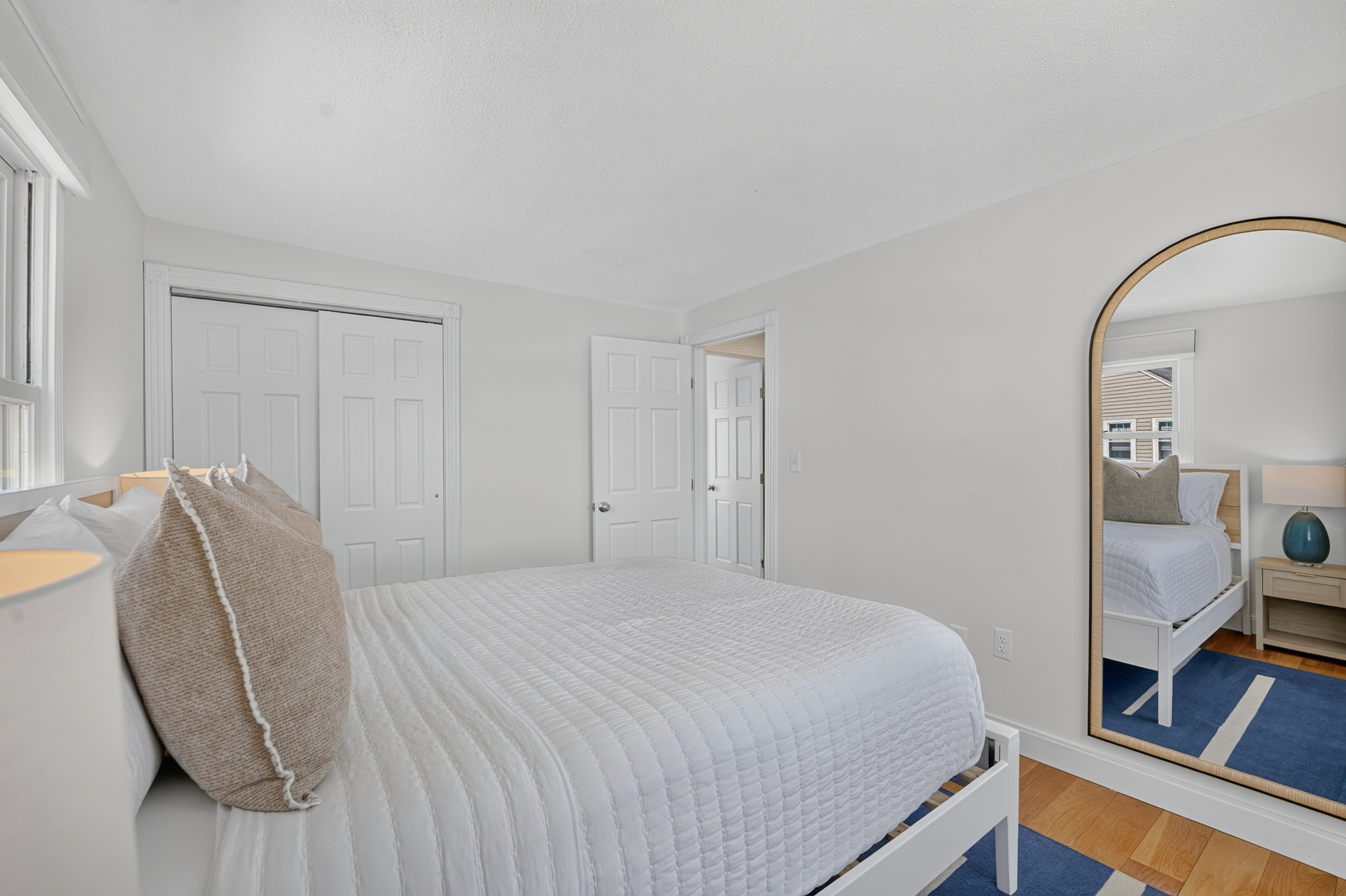Clean, peaceful bedroom with ample storage and a full-length mirror for added convenience.