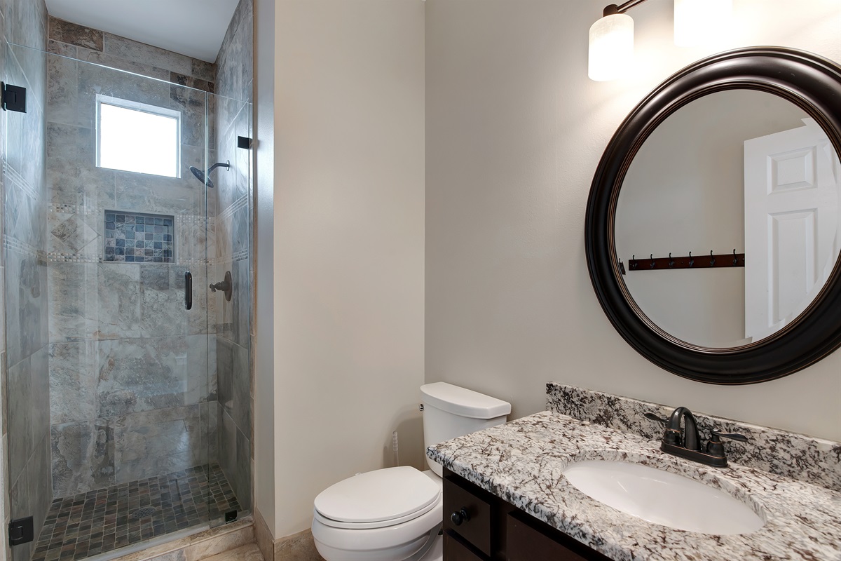 Bathroom with tiled walk‑in shower and granite vanity