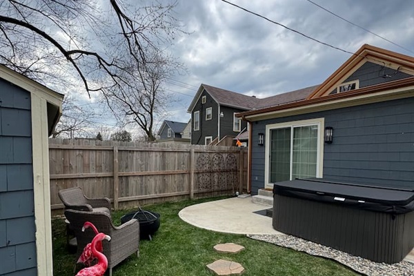 Private fenced backyard with a fire pit, lounge chairs, and charming stepping-stone path—ideal for gathering, unwinding, and enjoying outdoor living.