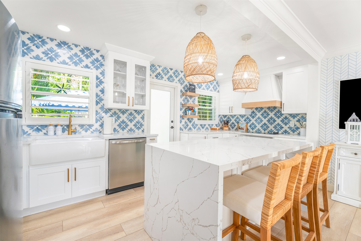 Cook and gather in this bright, Palm Beach&ndash;inspired kitchen featuring a large waterfall island, custom cabinetry, and stylish seating for easy entertaining.