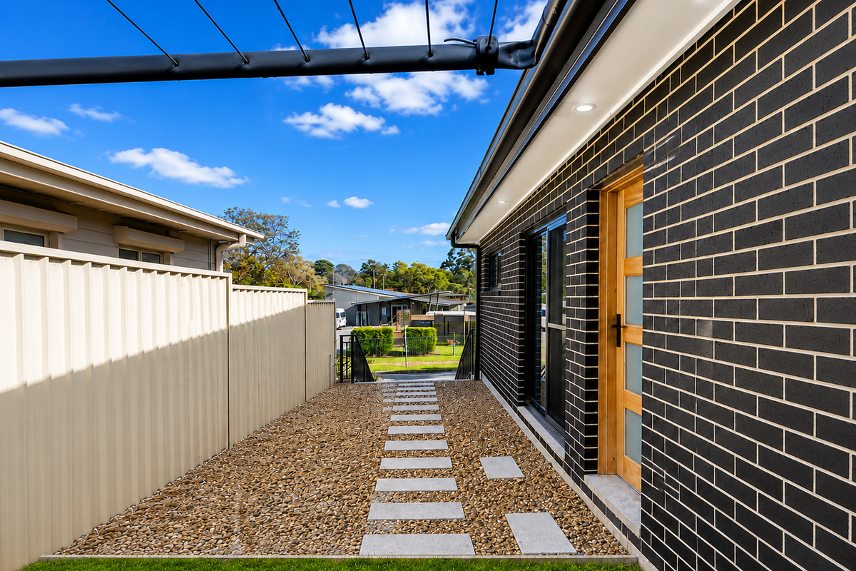 Matilda’s Urban Escape includes a side entry path with stepping stones leading along the black brick exterior.