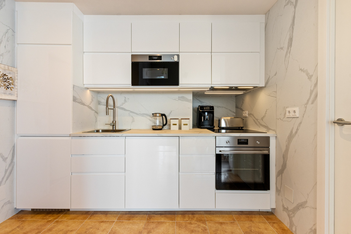 Modern kitchen with oven, microwave, coffee machine and everyday essentials.
