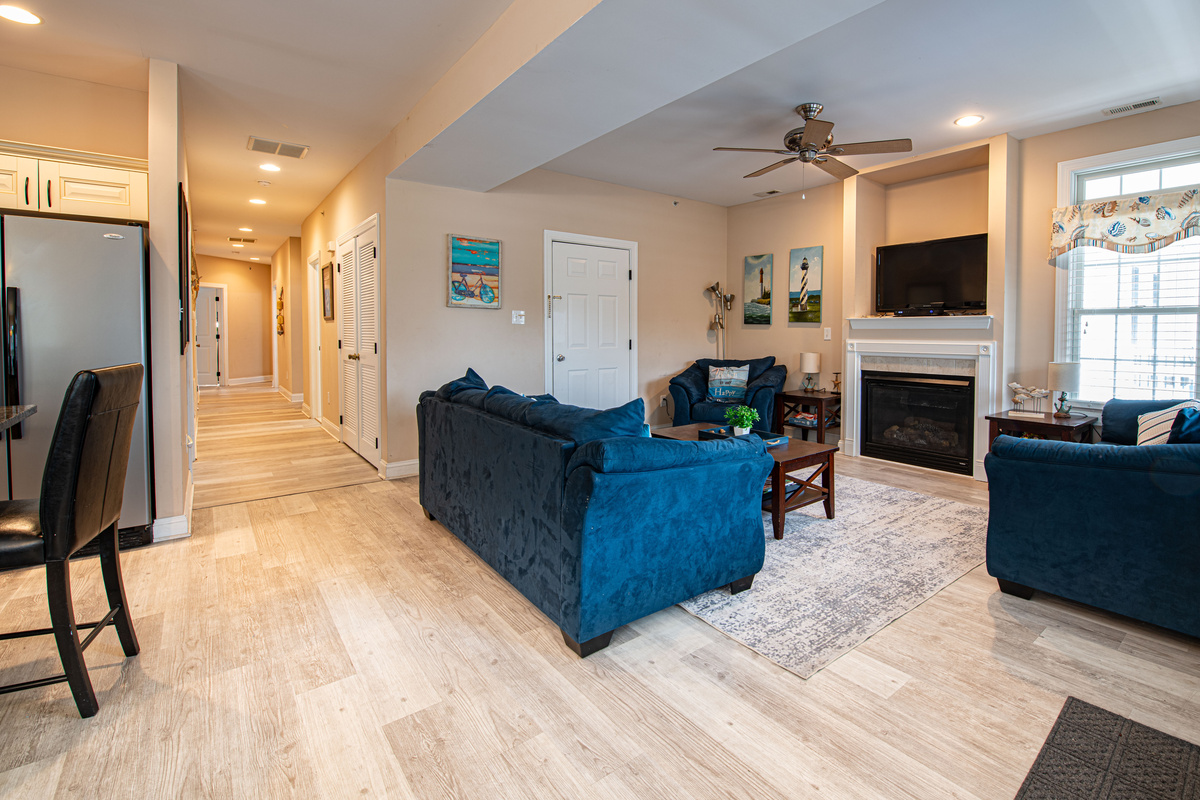 Living Room with Fireplace, Mounted TV, Blue Seating, and Hallway View